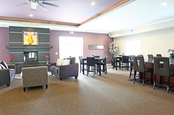 A living room with a grey carpet and a fireplace.